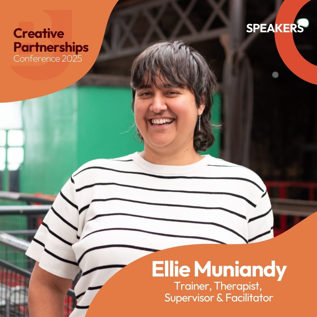 A person with short brown hair, smiling. They are wearing a white top with black stripes. Industrial background. Text reads: Creative Partnerships Conference 2025. Speakers. Ellie Muniandy. Trainer, Therapist, Supervisor & Facilitator.