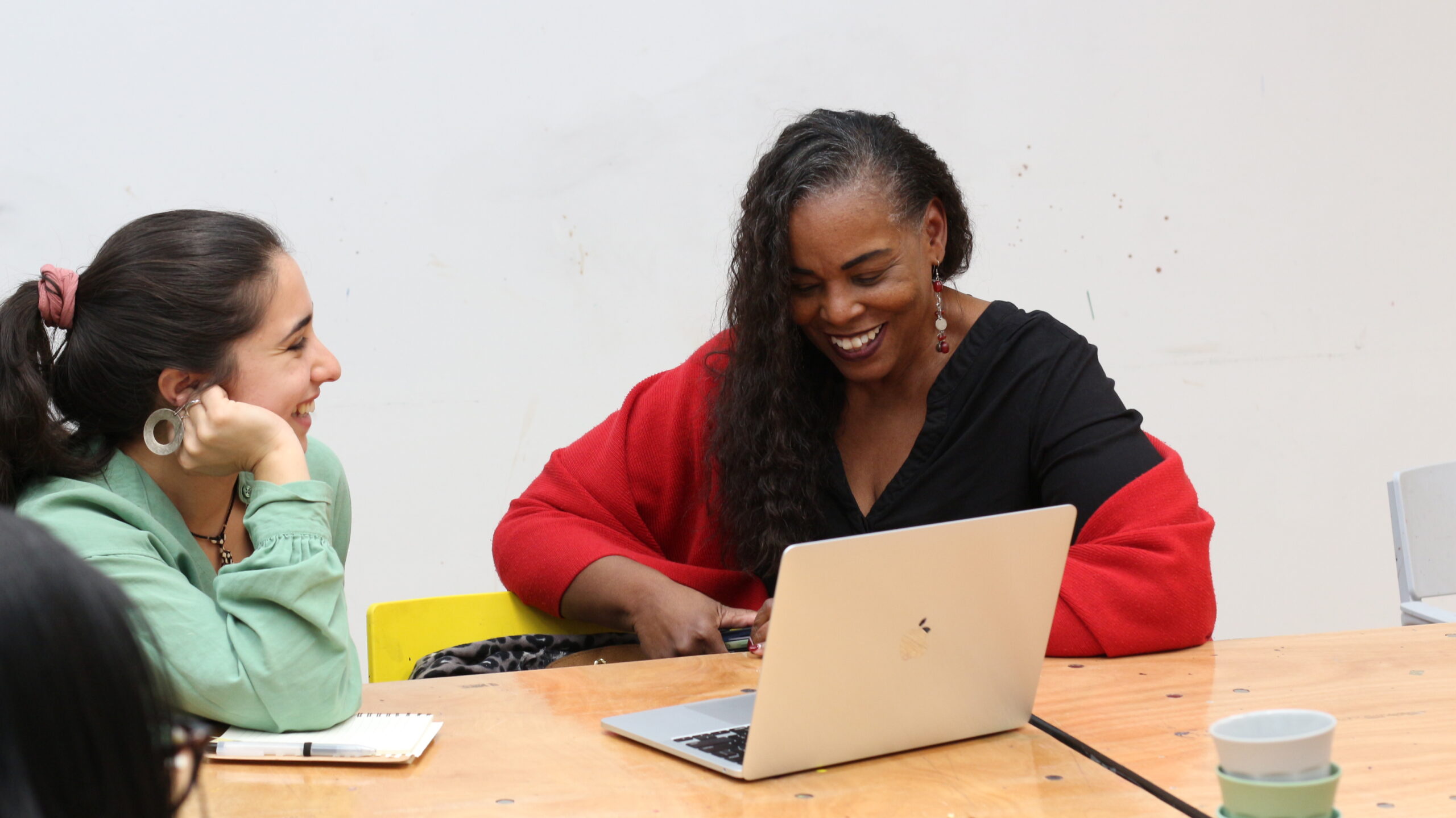 Two people smiling and laughing in front of a laptop